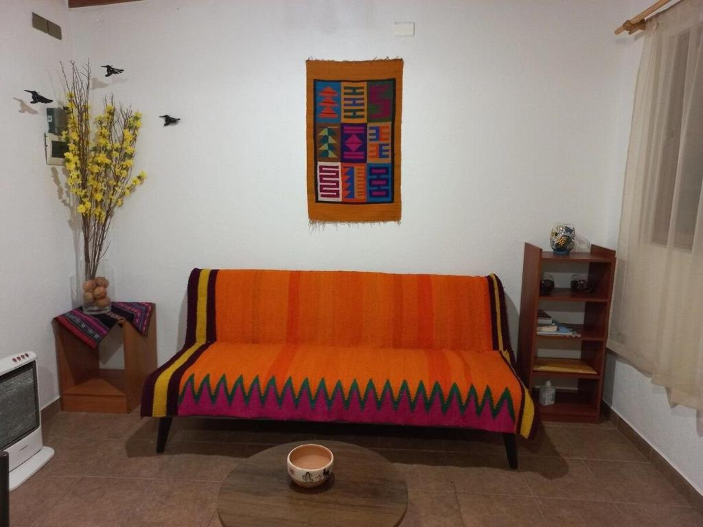 an orange couch in a living room with a table at Casa Sutar Las Higueras in San Pedro de Atacama