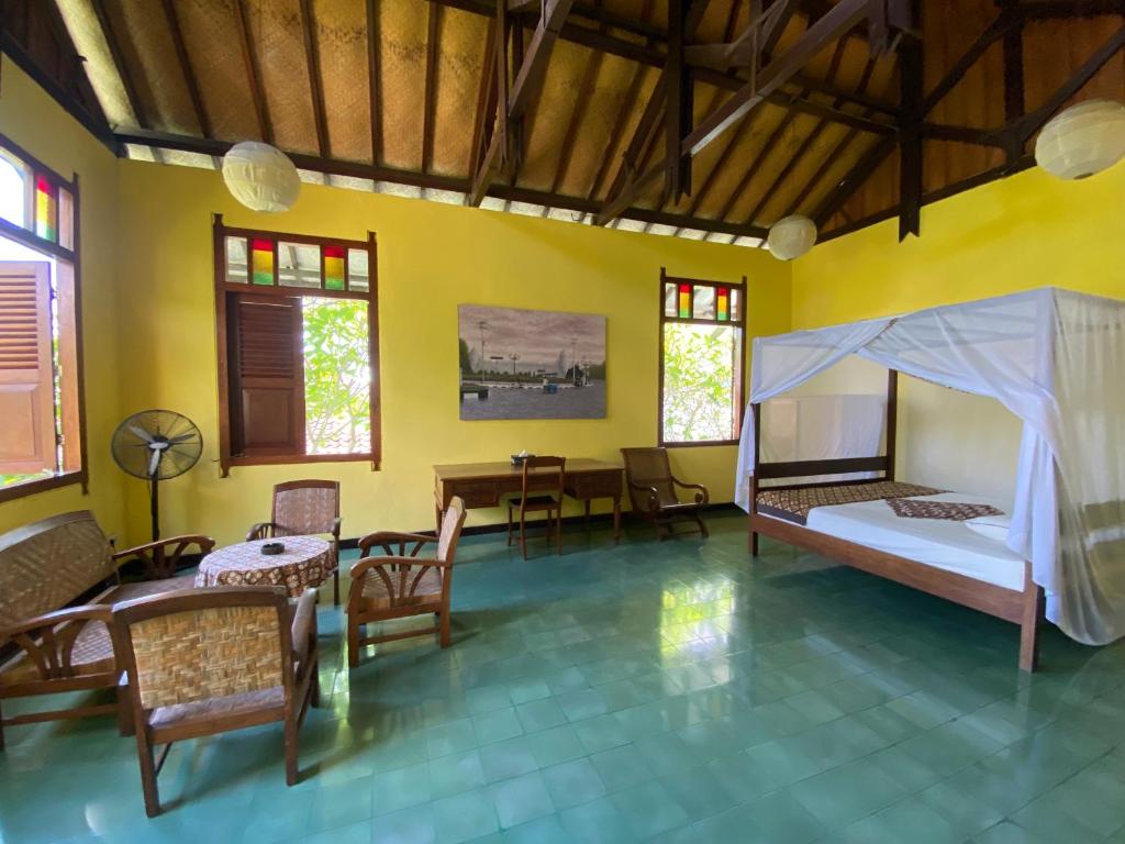 a room with a bed and a table and chairs at Villa Sambal in Yogyakarta