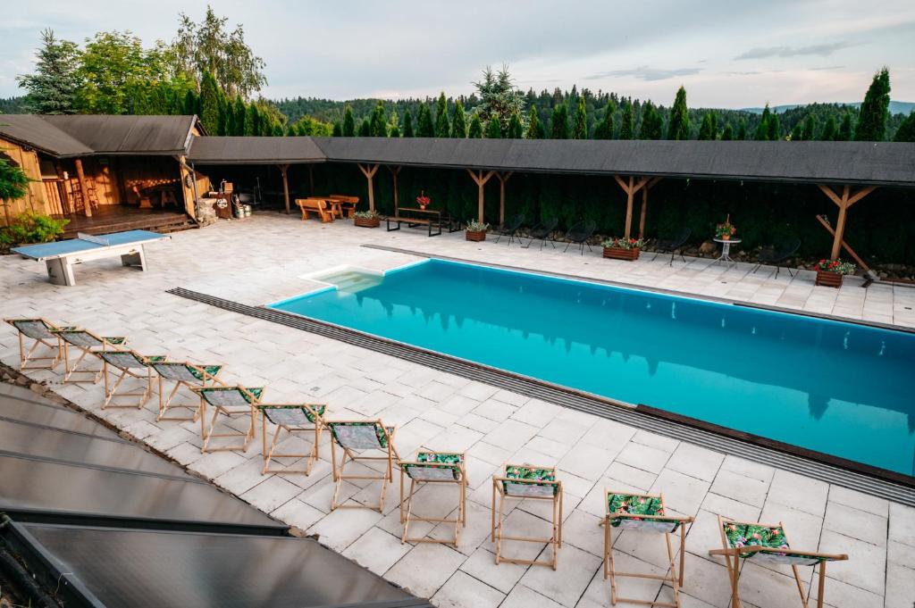 a swimming pool with chairs and a table at Bieszczadzka Bania in Lesko