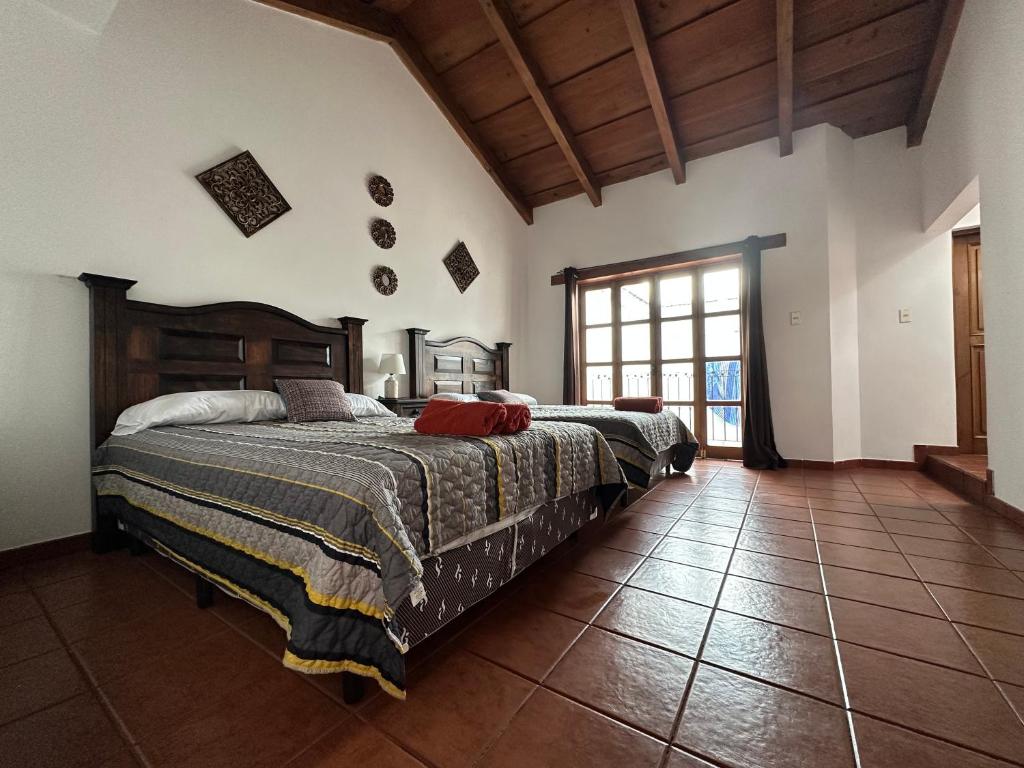 1 dormitorio con 2 camas y ventana grande en Casa Los Habitantes Antigua Guatemala en Antigua Guatemala