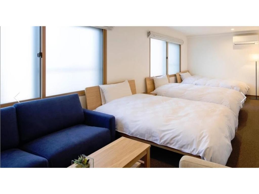 Habitación con 2 camas y sofá azul en ＳＯ Ｋｙｏｔｏ Ｆｕｓｈｉｍｉ Ｉｎａｒｉ - Vacation STAY 76154v, en Kioto