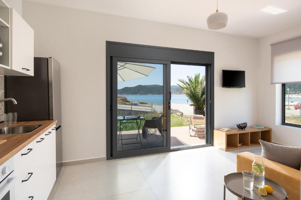 a kitchen with a sliding glass door with a view of the ocean at Saint John Luxury Seafront in Paralia Sikias