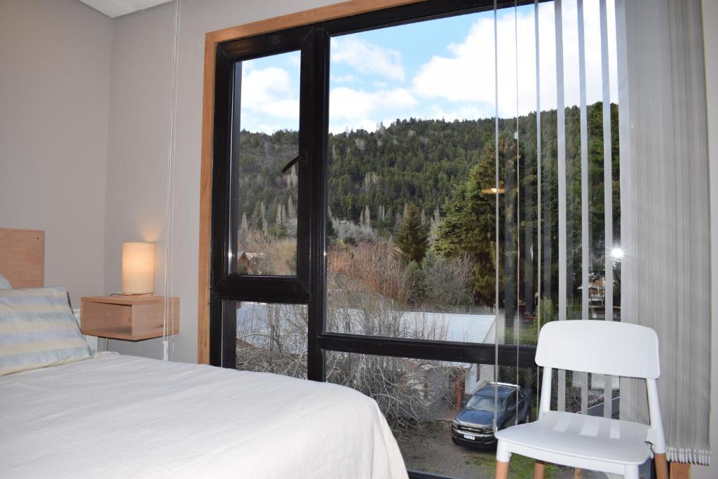 um quarto com uma cama e uma grande janela em Monoambiente Céntrico em San Martín de los Andes