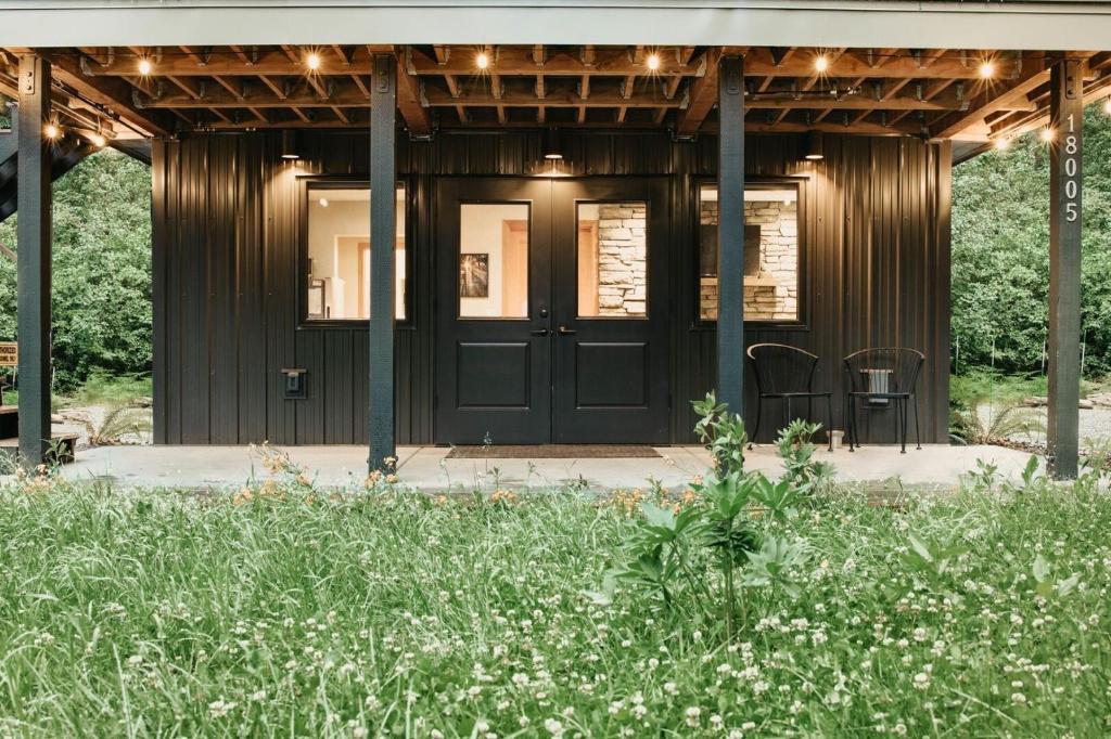 ein Holzhaus mit einer schwarzen Tür und einigen Blumen in der Unterkunft 08MBR - Starlink - Gas F P - BBQ - Sleeps 2 home in Glacier