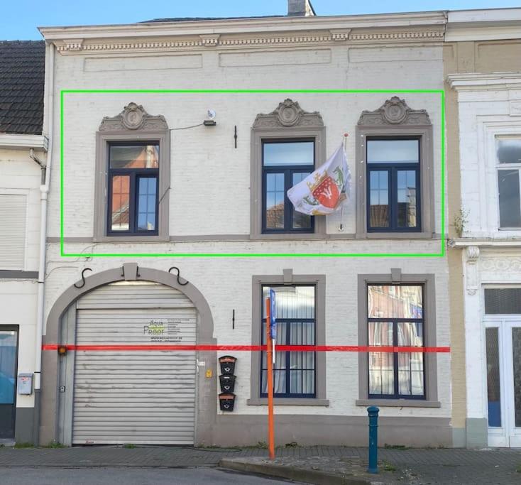 un edificio bianco con una porta del garage e una bandiera di The Sugar Cube a Tienen