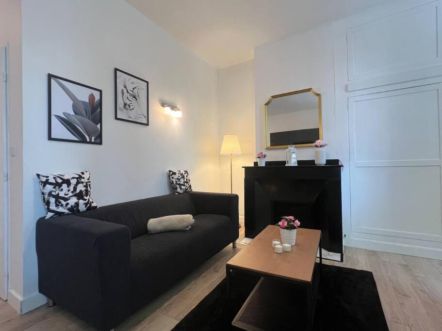 - un salon avec un canapé noir et un miroir dans l'établissement Le Castelet - Paisible T2 proche métro, à Toulouse