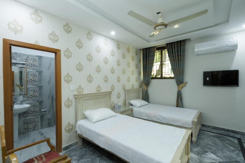 a bedroom with two beds and a sink and a mirror at Midways Guest House and Hotels in Islamabad