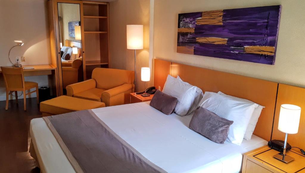 a hotel room with a bed and a chair at Cardum Hotel in Sorocaba