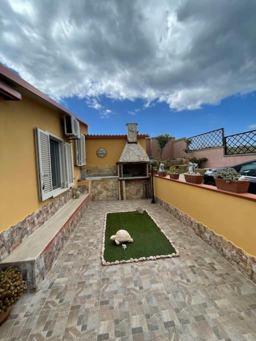 une terrasse avec une maison avec une tortue sur l'herbe dans l'établissement Casa Vacanze a 10 km dal mare, à Carbonia