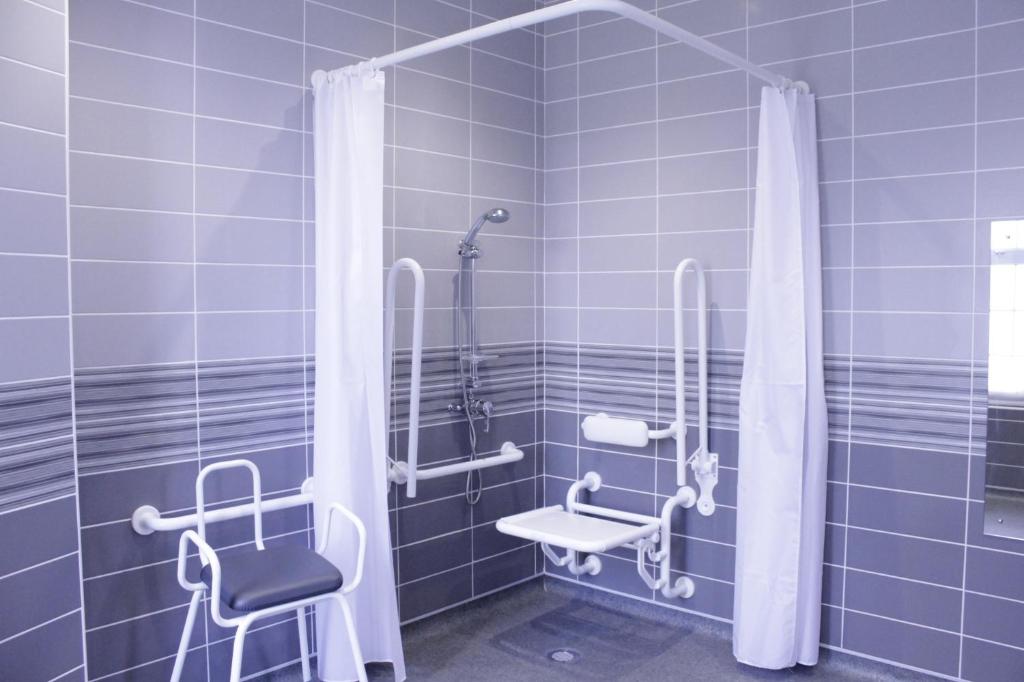 a blue tiled bathroom with a shower and a chair at Gwesty Seren Hotel in Blaenau-Ffestiniog