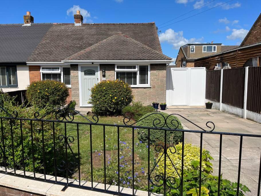 Idyllic bungalow, ideal location in West Lancashire في Burscough: منزل به سياج أمام ساحة