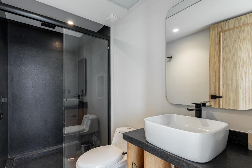A modern bathroom with a vessel sink, toilet and enclosed shower.