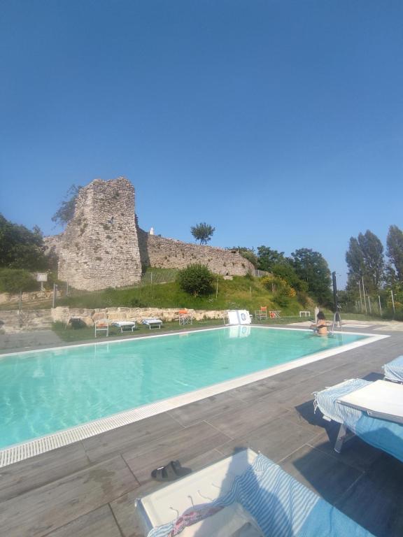 a large swimming pool with a castle in the background at Agriturismo Borgo San Benedetto in Pietralunga