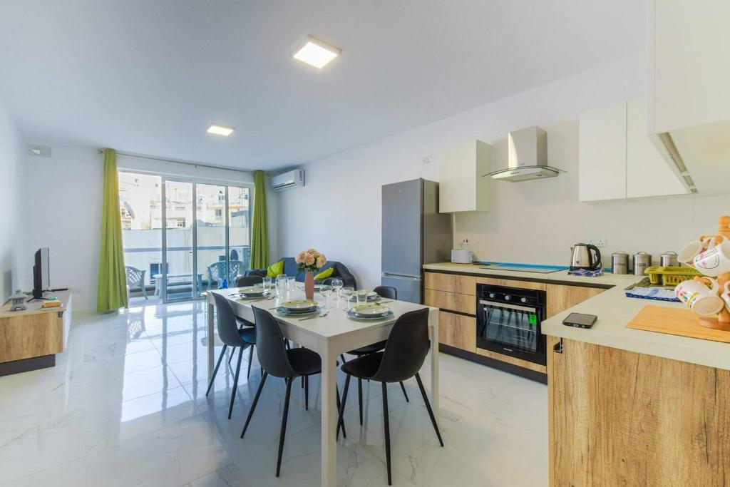 cocina con mesa y sillas en una habitación en Brand New Modern Apartment Bugibba 3Bdr 2 Bth, en St Paul's Bay