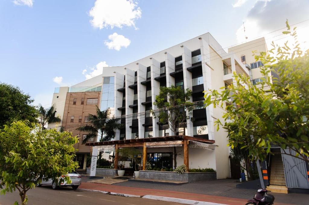 a white building on a street with trees at Pumma Business Hotel in Canaã dos Carajás