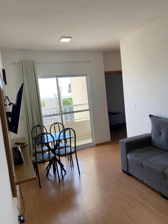 a living room with a couch and a table and chairs at Apês Palmeira Dourada - Centro de Palmas e Aromaterapia in Palmas