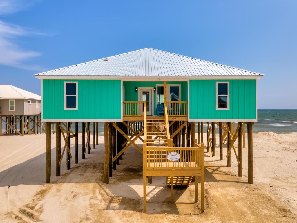 una casa verde en un muelle en la playa en Simply Blessed - 106 Vargas Ct home, en Dauphin Island