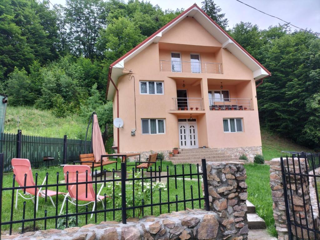 a pink house with chairs and a fence at Casă de vacanță Lidia in Albac