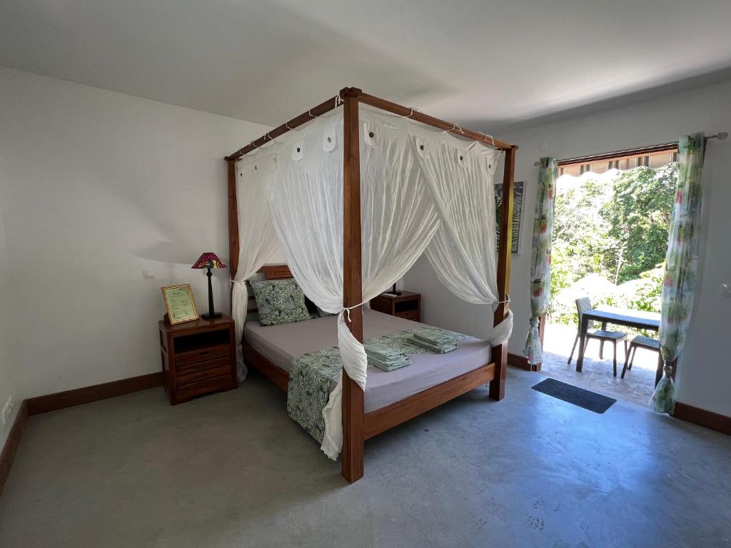 1 dormitorio con cama con dosel y ventana en Chambre Paradise, en Lamentin