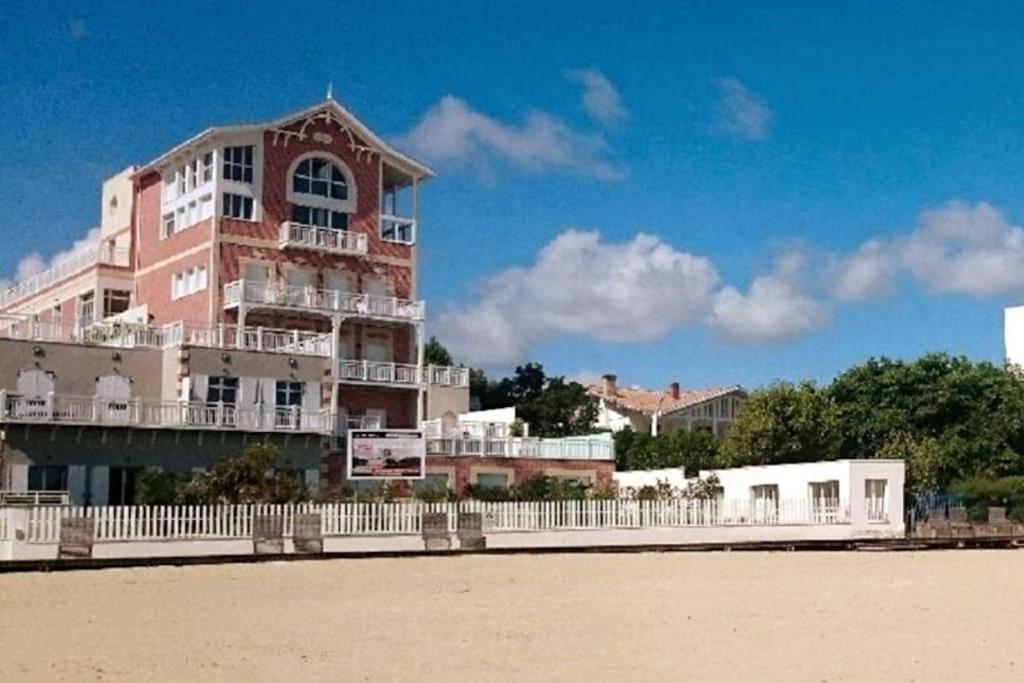 un bâtiment rose avec une clôture blanche devant une plage dans l'établissement Arcarêve - Grand Studio Deluxe avec terrasse, jardin et accès plage, à Arcachon