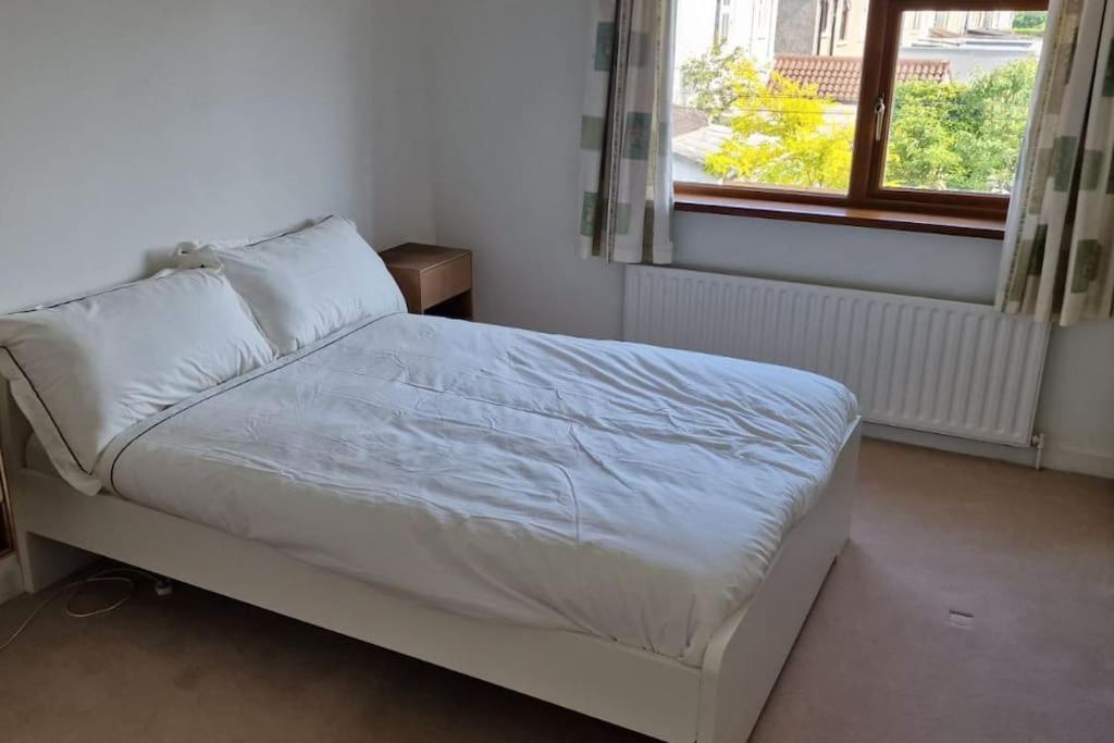 - un lit blanc dans une chambre avec fenêtre dans l'établissement Home in Monkstown, à Monkstown