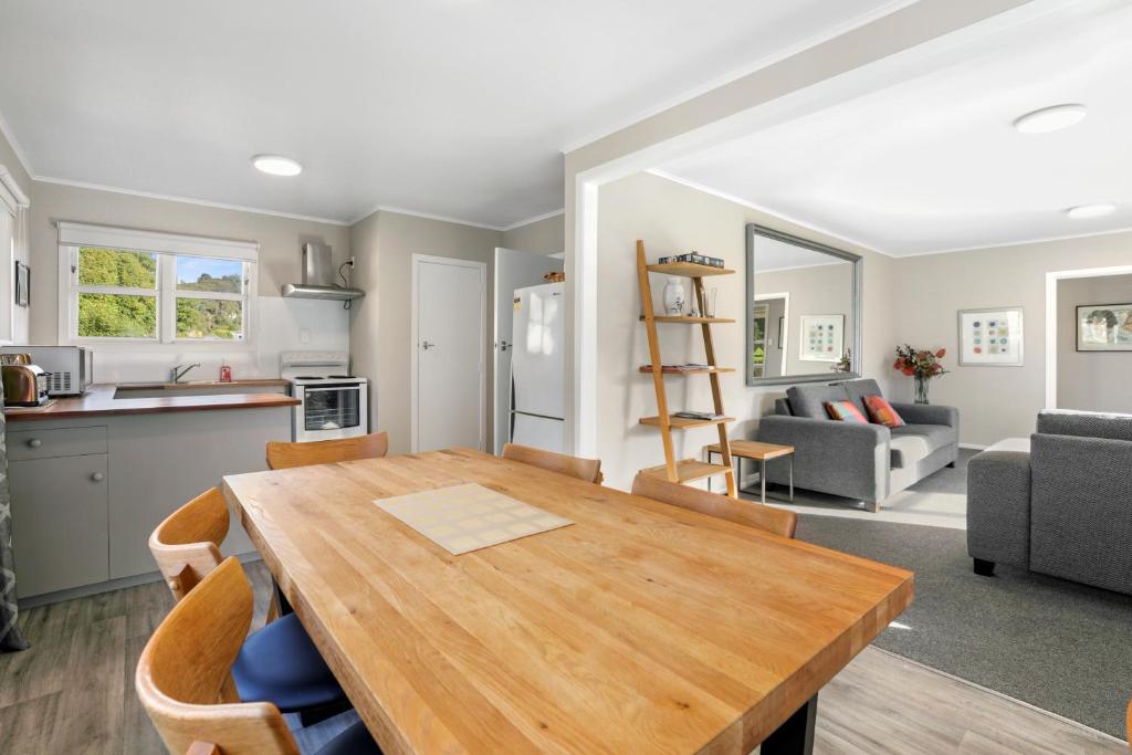 a kitchen and living room with a wooden table and chairs at The Greenkeeper's Cottage in Rotorua