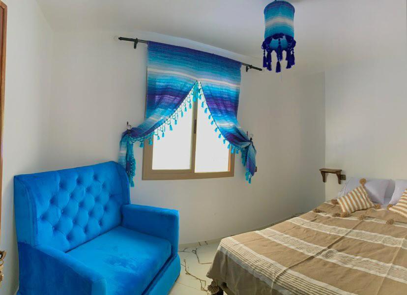 uma cadeira azul num quarto com uma cama em house naim em Chefchaouen