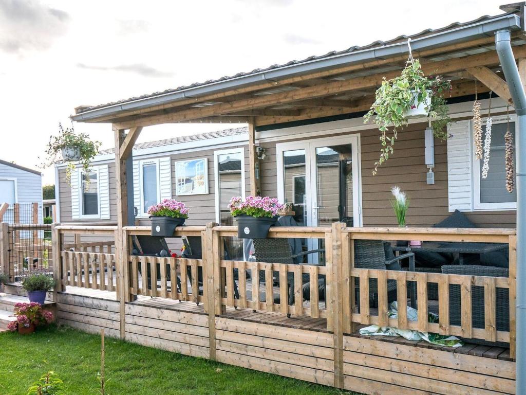 a house with a wooden deck with potted plants at Beautiful chalet in Oostkapelle with swimming pool in Oostkapelle
