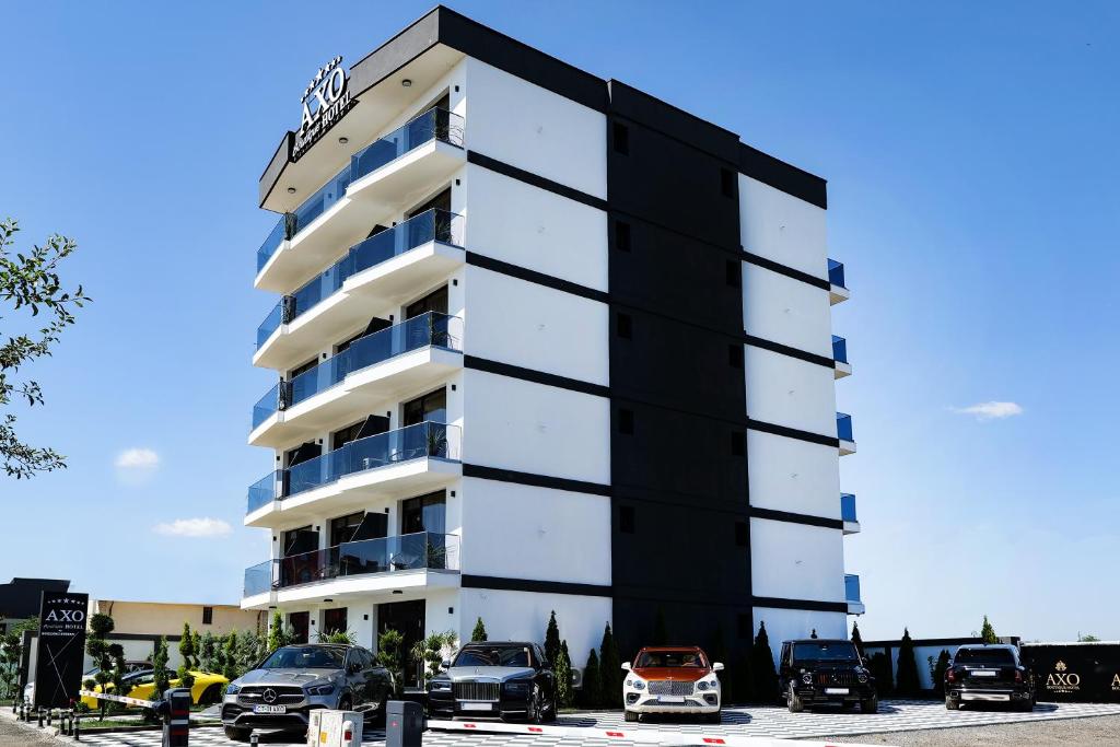 un edificio blanco y negro con coches estacionados en un estacionamiento en AXO Boutique HOTEL by BUILDING STEFAN, en Năvodari