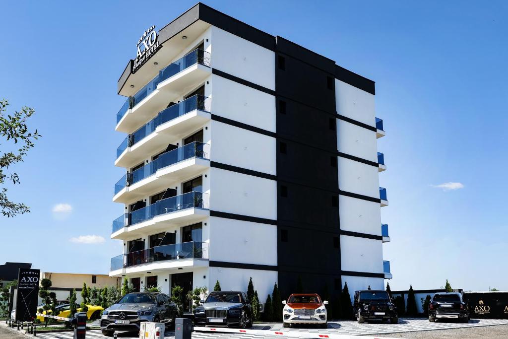 a black and white building with cars parked in a parking lot at AXO Boutique HOTEL by BUILDING STEFAN in Năvodari