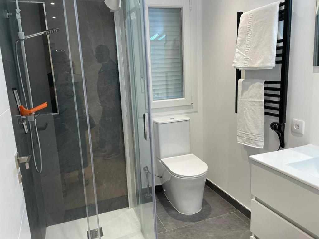 a bathroom with a toilet and a glass shower at Apartamento Mar de la Concha in Vilagarcia de Arousa