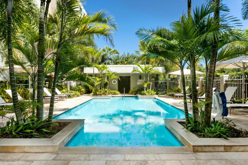 a swimming pool with palm trees in front of a house at Hyatt House San Juan in San Juan