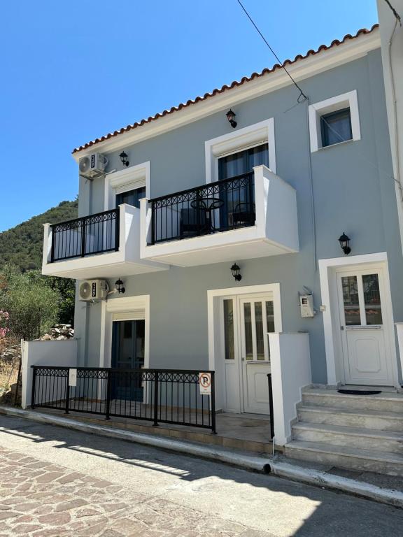 a white house with stairs and a balcony at Melinda’s cozy apartments in Plomarion