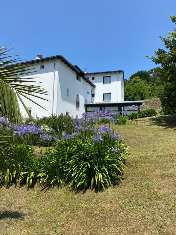 un edificio blanco con flores púrpuras en un patio en Finca Portizuelo, en Luarca