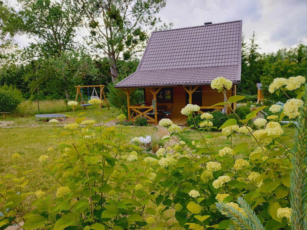 a small house in a garden with flowers at Zielony Zakątek in Kretowiny