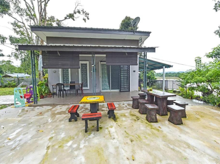 una pequeña casa con mesas y bancos frente a ella en Kampungstay by The LiliZ, en Pekan