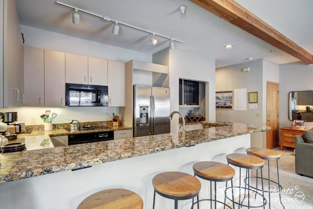 a kitchen with wooden stools and a counter top at Ski In & Out Townhome - Close Proximity to Summer Hiking Trails & Main St Breck ANT23 in Breckenridge