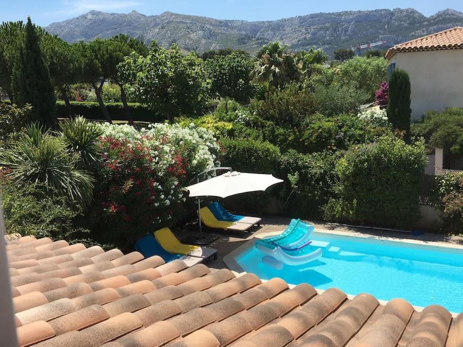 einen Pool mit 2 Stühlen und einem Sonnenschirm in der Unterkunft Maison avec piscine et vue sur les collines. in Marseille