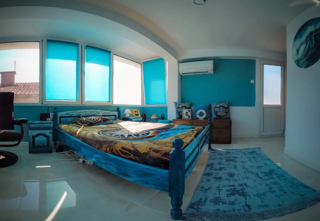 a bedroom with a bed with blue walls and windows at Casa Del Mare in Chernomorets
