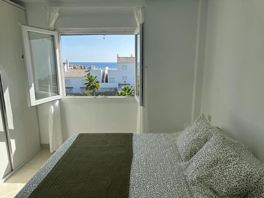 ein Schlafzimmer mit einem Bett und einem großen Fenster in der Unterkunft Idílica casa en Atlanterra in Zahara de los Atunes