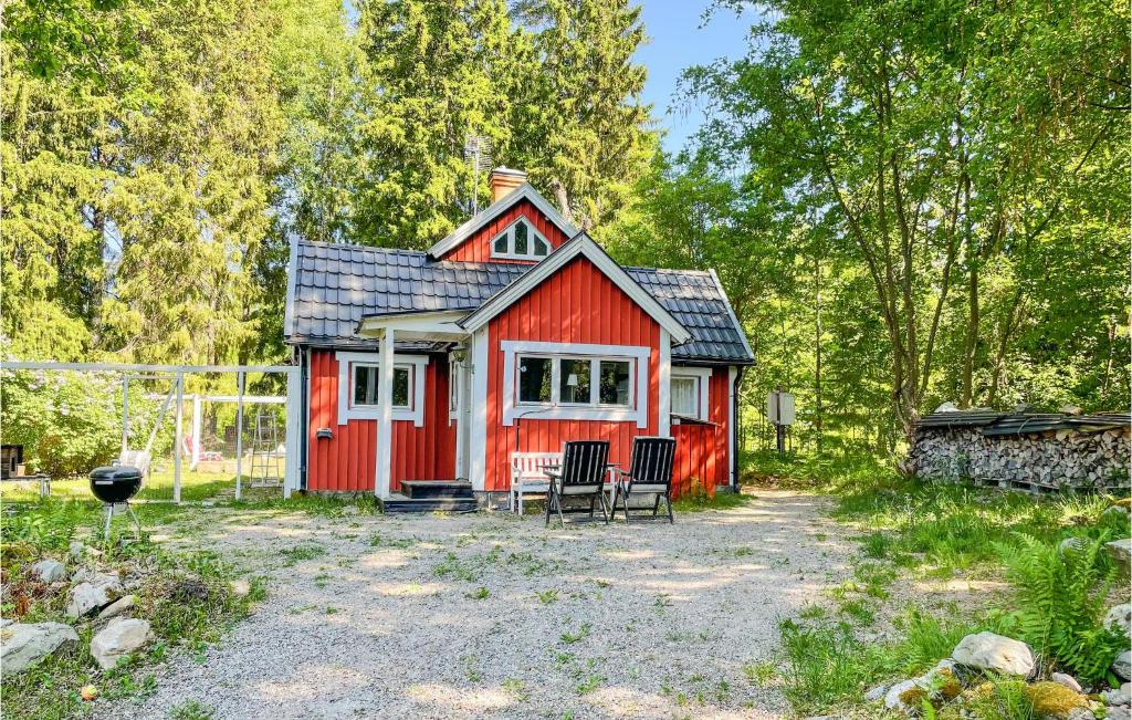 a red house with two chairs in front of it at Cozy Home In rebro With Wifi in Örebro