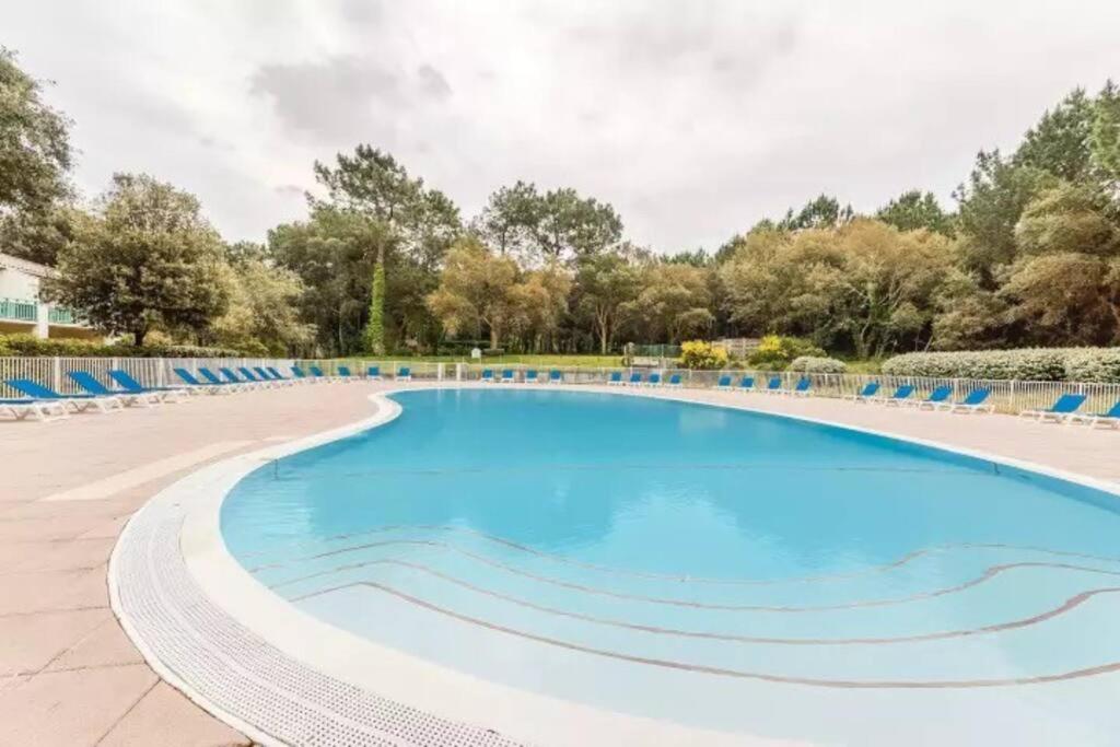 una gran piscina con sillas azules alrededor. en appartement T3 Soustons plage Vieux Boucau océan, en Soustons