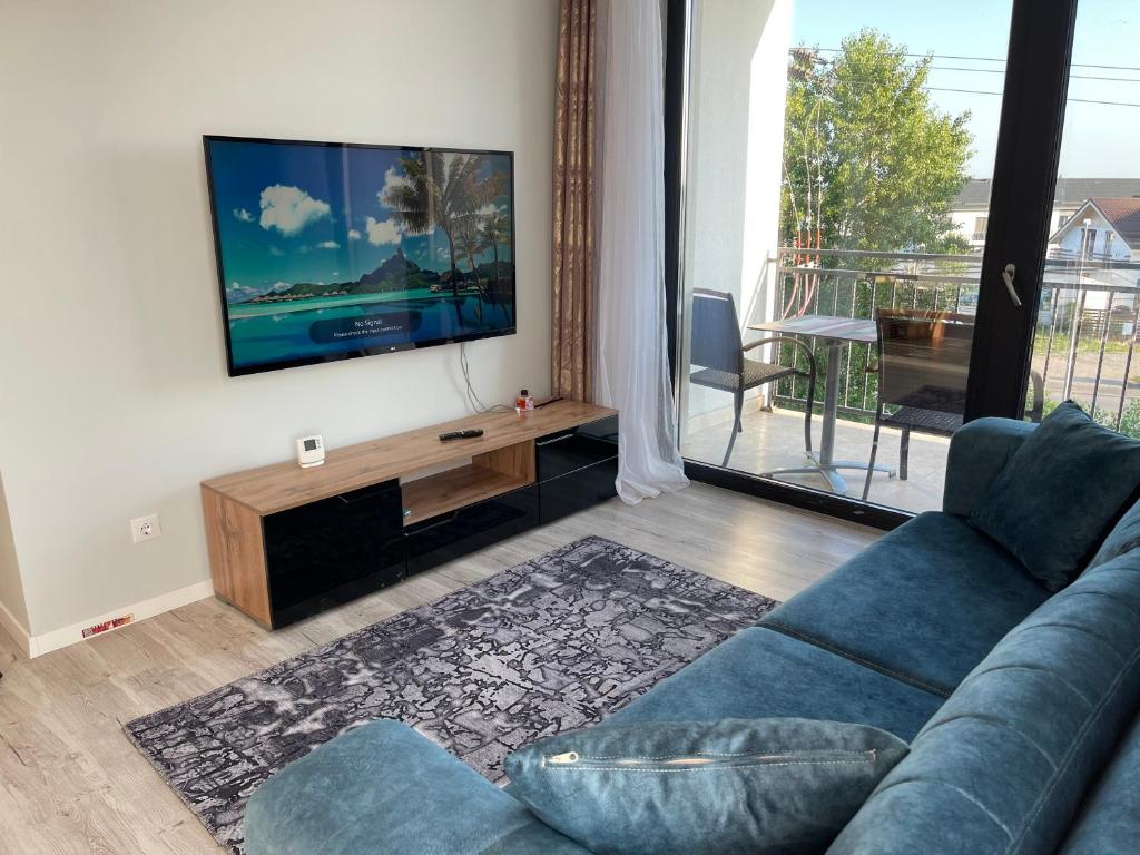 een woonkamer met een blauwe bank en een flatscreen-tv bij Noah Apartment Self Check-in Otopeni in Otopeni
