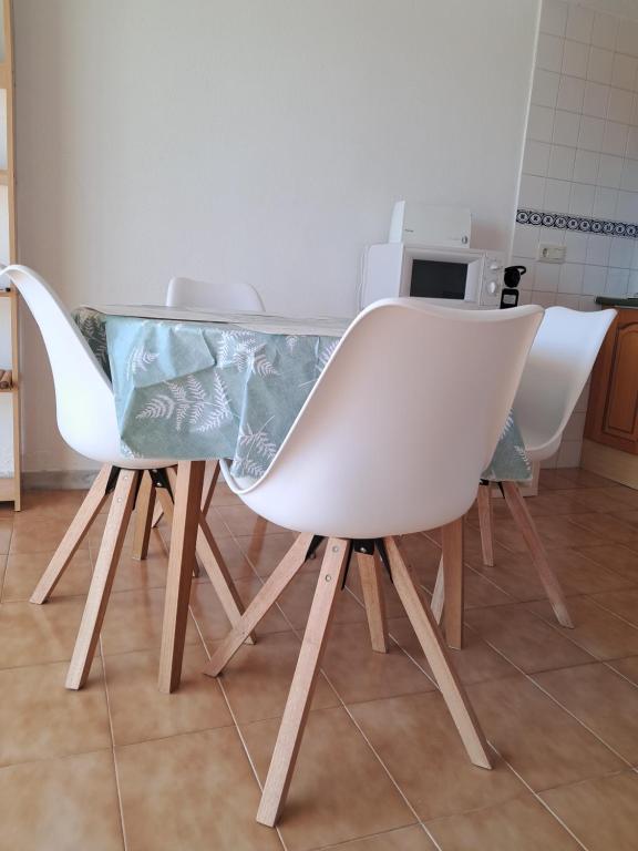 una mesa con tres sillas blancas sentadas a su alrededor en Brisas del Mar Azul, en Torrevieja
