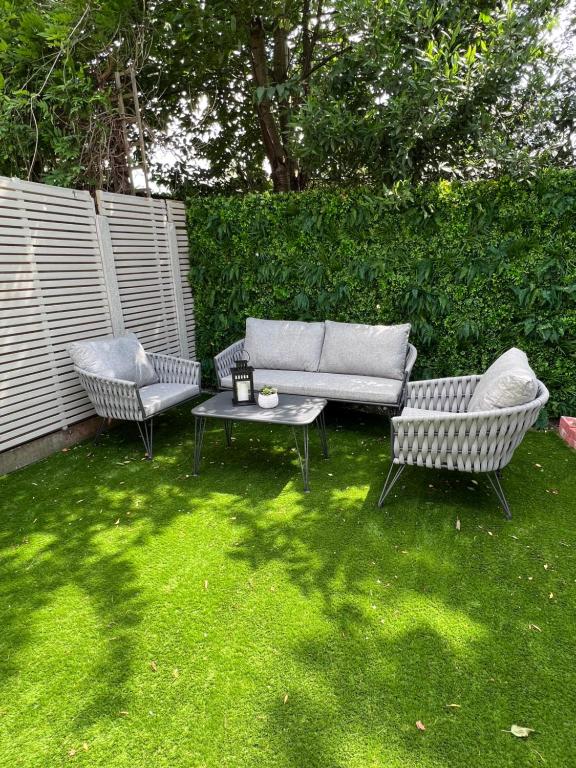 een tuin met 2 stoelen, een bank en een tafel bij Beautiful 5-bedroom private house in quiet London street 2 minutes from station in Londen