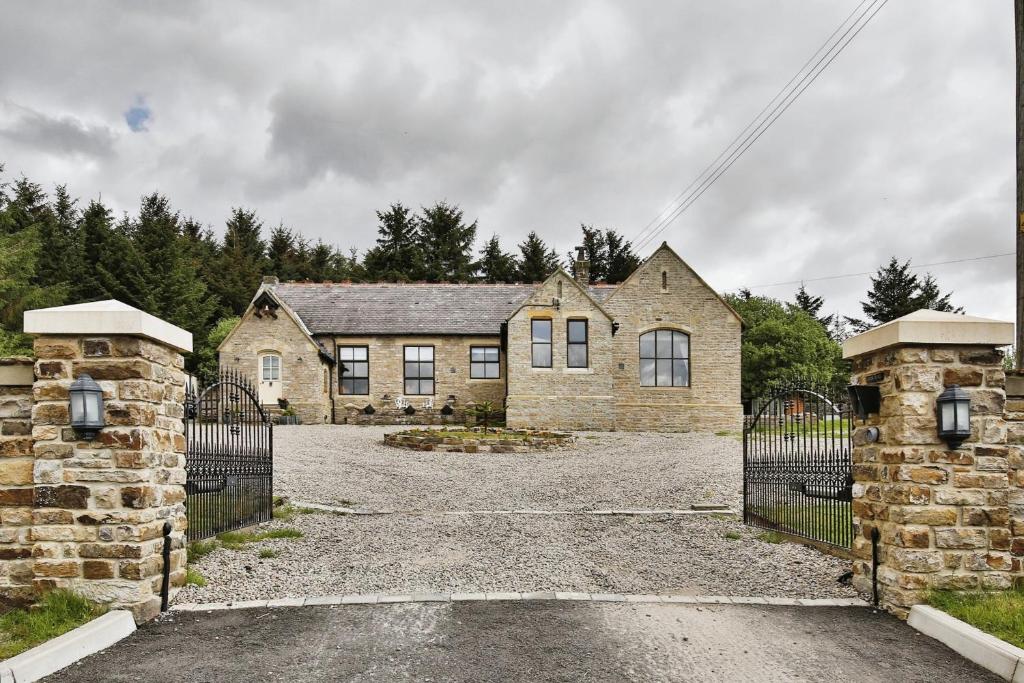 an old stone house with a gate in front of it at Lanehead Old School in Lanehead