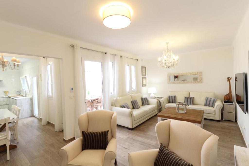 una sala de estar con muebles blancos y una lámpara de araña. en Sitges Centre Mediterranean House- 5 Bedroom, 4 Bathroom, Terrace Courtyard, Private Rooptop Pool, en Sitges