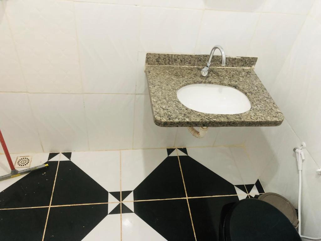 uma casa de banho com lavatório e piso em azulejo preto e branco em Pousada Voadores Jalapão em Mateiros