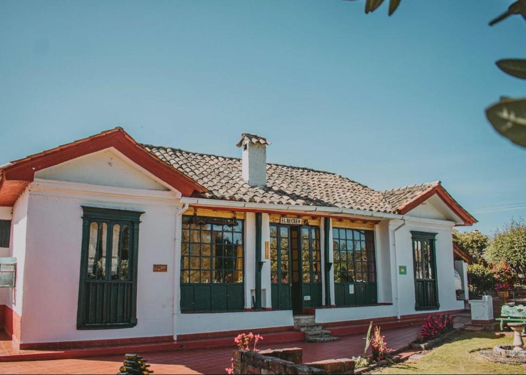 una piccola casa bianca con finestre nere di Hotel Finca el Recreo a Guasca