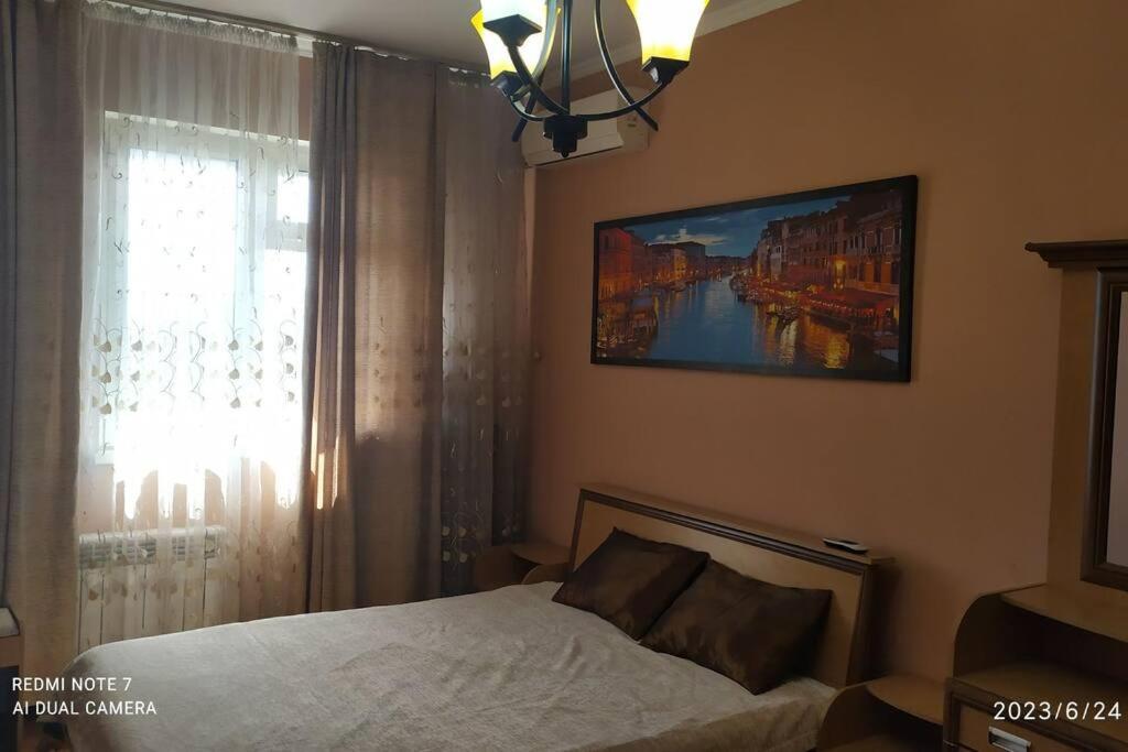 a bedroom with a bed and a window with a painting at Elegant Condo next to Bazaar, close to the metro station, 9 in Tashkent